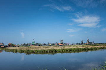 Dutch windmills in a blue sky summer day in the Netherlands polder - obrazy, fototapety, plakaty