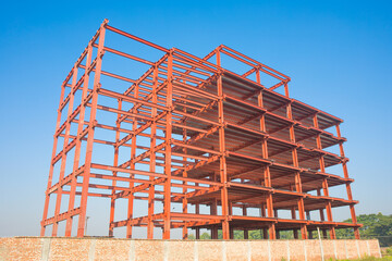 Red steel beam construction site against a bright blue sky