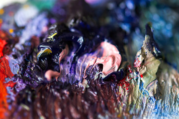 Mixing purple and pink oil paint close-up on the artist's palette. Hobbies and leisure. Top view of the palette. Abstract art background. Creative process. Selective focus.