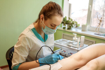Doctor is doing hair removal, electro epilation to the clinet. Indoors in the clinic. Doctor is wearing mask and gloves. 