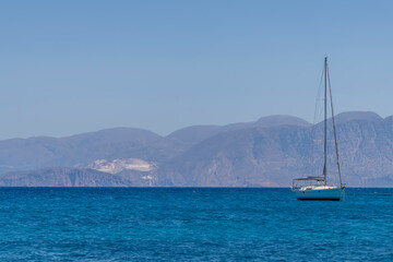 Obraz premium Summer sea view from coast with white yaht and mountains in background, Greece
