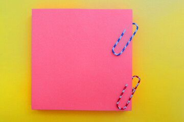 orange sticky blanks colored paper clips on a yellow background, mock up, flat lay