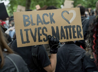 A close-up shot of a caucasian protester carrying a Black Lives Matter Placard in Hyde Park, London