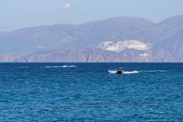 Fototapeta na wymiar Summer sea view from coast with white yaht and mountains in background, Greece