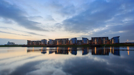 Quayside Apartment Building at night with reflections in the water and beautiful clouds. 