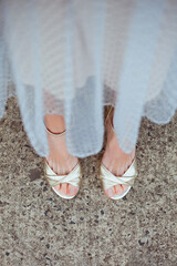 Fashionable young woman in gold high heel shoes and beige tulle midi skirt on the city street. Street style.