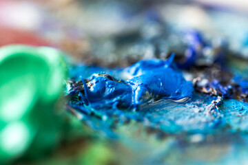 Blue oil paint close-up on the artist's palette. Hobbies and leisure. Top view of the palette. Abstract art background. Creative process. Selective focus. Ceruleum blue hue paint.