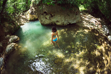 A woman in a swimsuit swims in a mountain river.