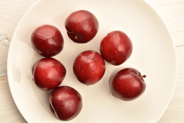 Juicy, tasty, organic red plum, close-up, on a painted wooden table.