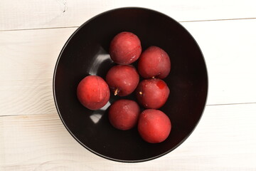 Juicy, tasty, organic red plum, close-up, on a painted wooden table.