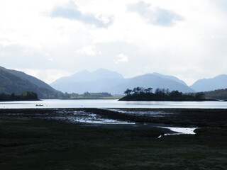 Lake with mountains and trees beyond at dusk