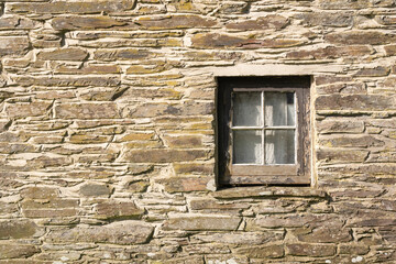 Fototapeta na wymiar Old square window frame and stone wall in building in Felindre Farchog, near Newport. Pembrokeshire, Wales. UK