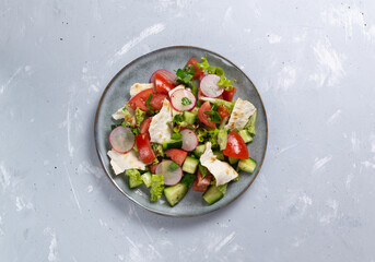 Fototapeta na wymiar Vegan fattoush salad in a gray plate on a gray background. Copy space. Top view. Levantine salad fattoush, which is prepared from dried pita or pita with the addition of various vegetables and herbs. 
