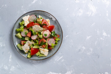 Fototapeta na wymiar Fattoush vegetarian salad in a gray plate on a gray background. Copy space. Top view. Levantine bread salad, which is prepared from dried pita bread with the addition of various vegetables and herbs. 