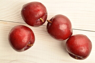 Juicy, tasty, organic red plum, close-up, on a painted wooden table.