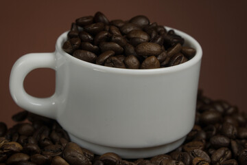White mug with coffee grains sprinkled with coffee grains on a background