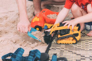 Father's day. Dad and son. Little son plays toys with dad on the beach with sand. Happy loving family. Happy family father and child. Toy cars. Hands of a man and a small child on the beach. Together
