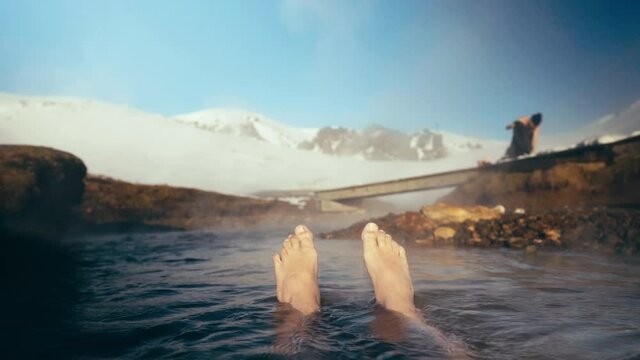 Feet floating in a natural hot spring lake in Iceland winter time