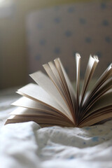 Open book on a bed. Selective focus.