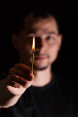 Hand with a burning match stick and blurred face of a man