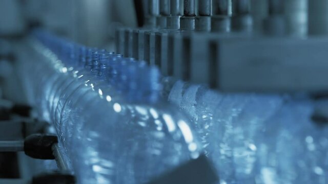 At factory bottles with clean water are conveyed along conveyor.