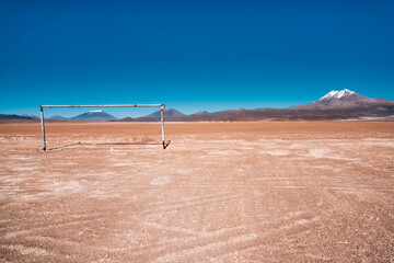 Lost soccer field in the desert at the top of the Andes with goal framing mountains in blue sky