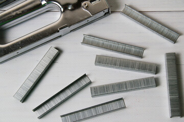 Concept of repair and construction. Construction stapler with brackets on a gray background top view