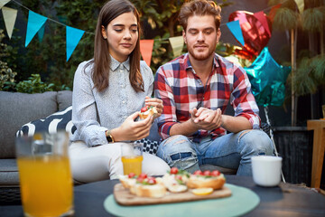 Man and woman eating jummy sandwiches outdoor