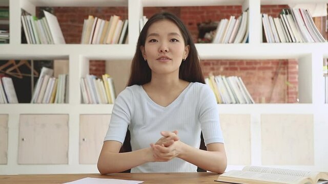 Happy asian girl student blogger talking to camera recording video blog, smiling chinese korean young woman coach teacher looking at webcam making video call online teaching sit at desk in library