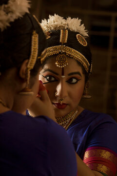 Bharatanatyam dancer applying kajal while looking in mirror