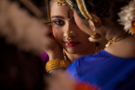 Bharatnatyam dancer applying kajal in her student’s eyes. 

