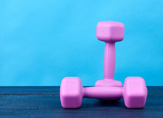 pink plastic dumbbells of one kilogram on a blue background