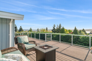Wicker chairs surrounding a rectangular fire pit on an outdoor wooden deck with a fantastic view of...