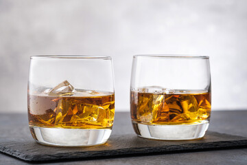 Two glass with whiskey on gray stone background