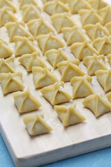handmade manti (turkish ravioli type dumplings) on wooden cutting board, before cooking 