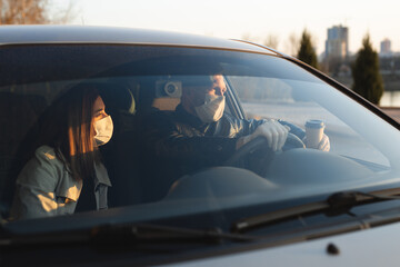 A man and a woman wearing medical masks and rubber gloves to protect themselves from bacteria and viruses while driving a car. masked men in the car. coronavirus, covid-19.