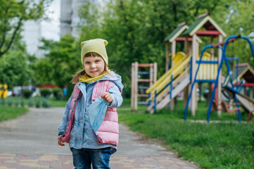 Little girl walking to the kids playground holding protective face mask after the end of quarantine. Pandemic COVID-19 is over concept.