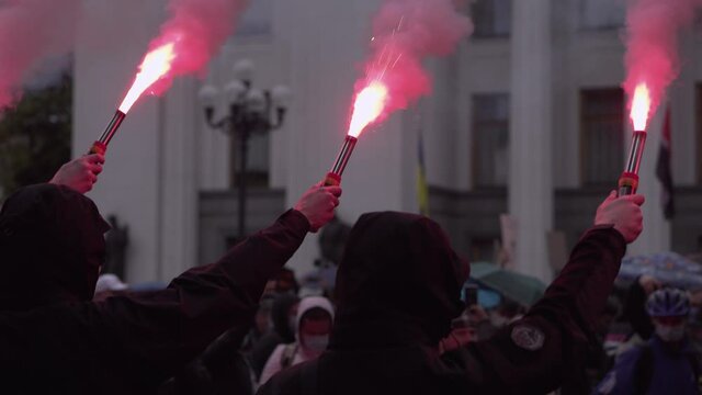 Protesters in their hands holding burning fires. Hands with flaming and smoking torches close-up. Riots and hooliganism on the streets of the city. Clashes with police during riots