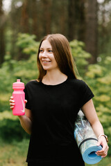 Beautiful young girl in sports uniform with a bottle of water doing yoga and sports in the forest in the open air