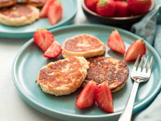 Sweet cheese pancakes on plate served strawberries. Cottage cheese pancakes, syrniki, ricotta fritters, curd fritters, Copy space for text or design.
