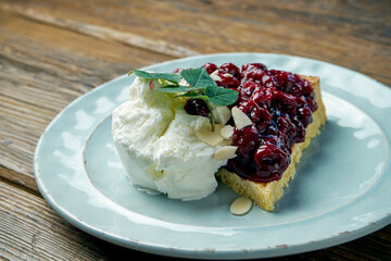 Appetizing dessert - cherry pie with vanilla ice cream in a plate on a wooden background