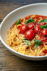 Homemade, Italian pasta - spaghetti with tomatoes and cheese in a bowl on a wooden background