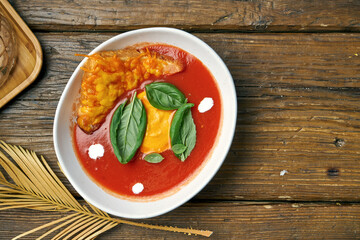 Classic spanish tomato gazpacho soup with cheese croutons in a white bowl on a wooden background
