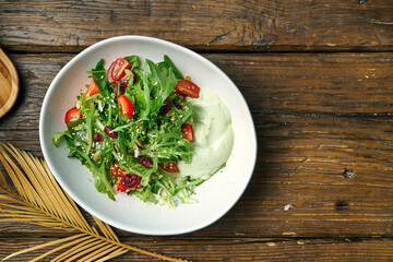 Vegetarian salad with cherry tomatoes, avocado mousse and strawberries in a bowl on a wooden background