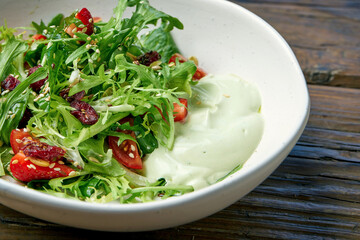 Vegetarian salad with cherry tomatoes, avocado mousse and strawberries in a bowl on a wooden background