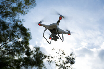 White drone with camera flying in summer mountains under storm clouds