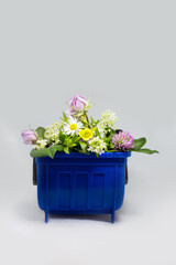 Plastic blue garbage trash bin can container with flowers, organic natural rubbish waste concept, beauty and dirty contrast at isolated background 