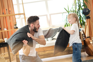 Father and daughter. Handsome young man and little cute girl pillow fight on a sunny day. Play with each other, actively spend time. Father's day. - Powered by Adobe