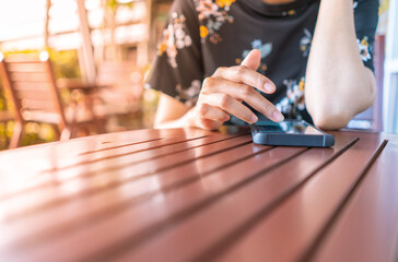 female hands with smartphone on wooden table in cafe