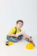 a small boy in a Builder's suit makes repairs on a white background